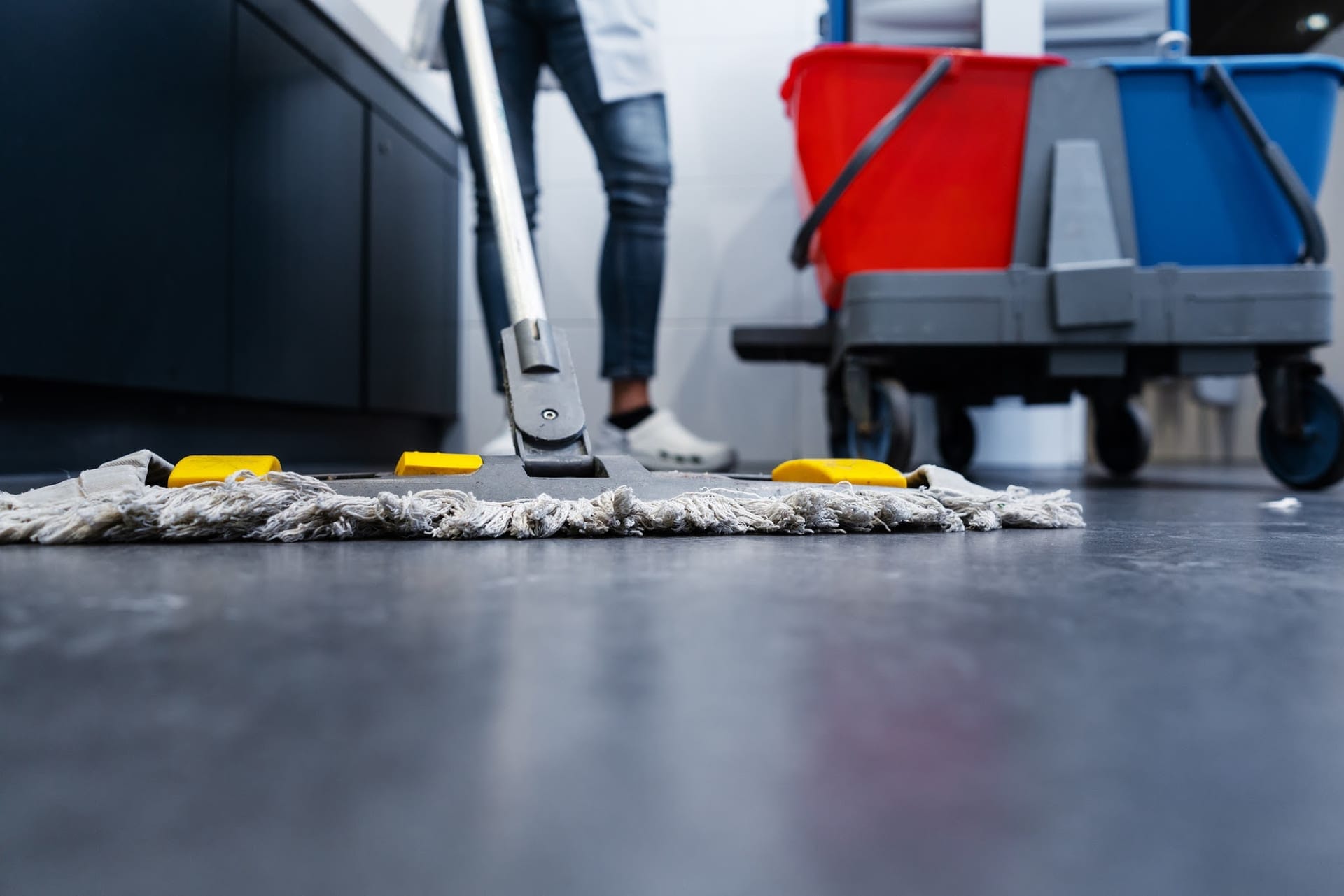 Mopping av eit mørkt golv ved sida av ei vasketralle